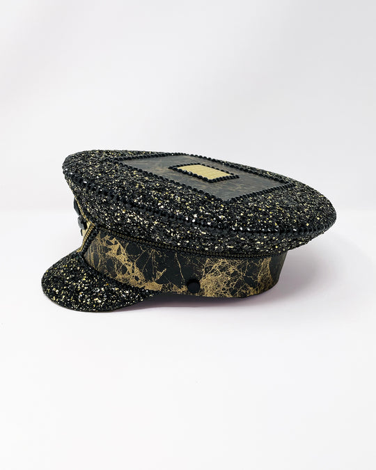 Authentic up cycled military captain hat, fully lined, hand embellished with black and gold glitter mix, beautifully hand detailed with gold and brown marble effect faux leather, gold leatherette, crystals and rhinestones. costume hat, festival hat, festival outfit, statement hat, high end hats, high end party wear, where to buy captain hats, stage wear, unique fashion, custom stage wear, festival essentials, festival headwear, halloween outfit, burning man hat, army hat, made in the UK