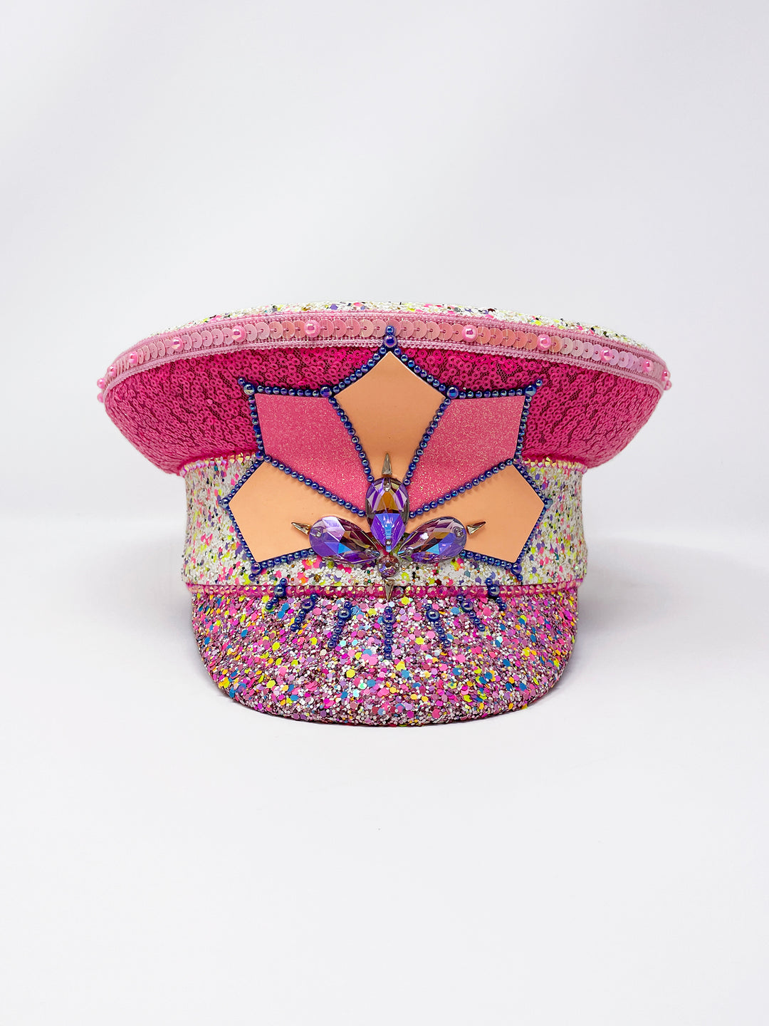 Festival captain hat with pink sequins, colourful glitter peak, Jukebox logo jewel detail, and glow-in-the-dark reflective starburst design – perfect for rave, costume, or party wear.
