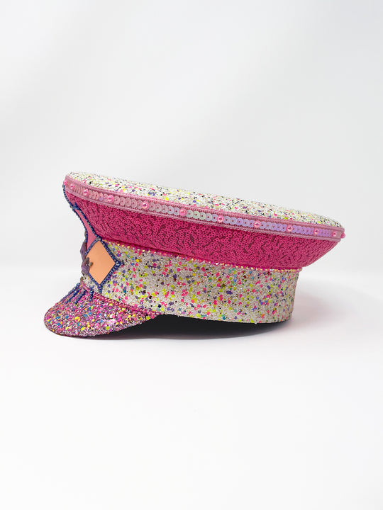 Festival captain hat with pink sequins, colourful glitter peak, Jukebox logo jewel detail, and glow-in-the-dark reflective starburst design – perfect for rave, costume, or party wear. Festival 
fashion,, stage wear